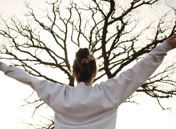 woman in white long sleeve shirt standing near bare tree during daytime
